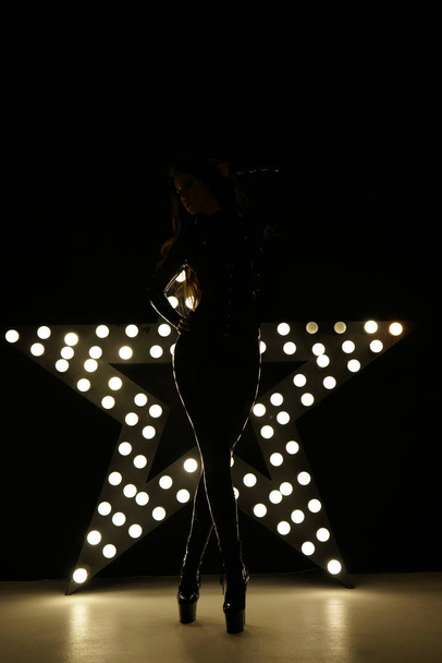 heiße kaukasische Frau posiert in erotischem Latex Gummi versauten Kostüm allein in der Nähe des Lichtstars - Foto, Bild
