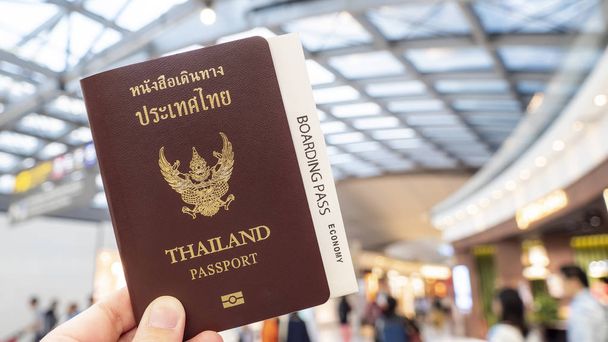 Mujer con pasaporte tailandés y tarjeta de embarque en la mano en la sala de pasajeros del aeropuerto
 - Foto, Imagen
