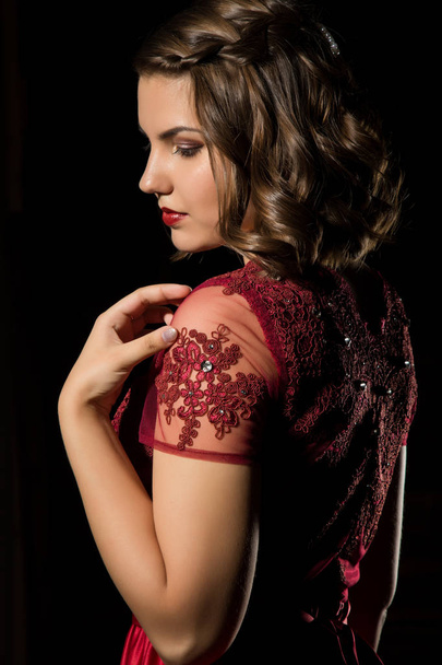 задумчивая красивая женщина в красном платье на темном фоне. профессиональная прическа и макияж
 - Фото, изображение