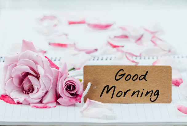 Writing good morning on card with rose on notebook.  - Foto, imagen