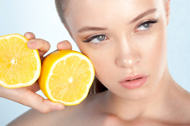 Young beautiful girl with clean perfect skin with lemon close-up. Beauty portrait - Фото, изображение