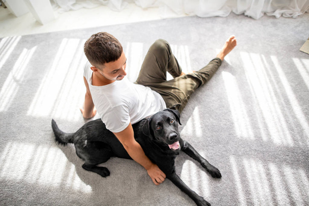 guy with his dog sitting at home playing - Фото, изображение