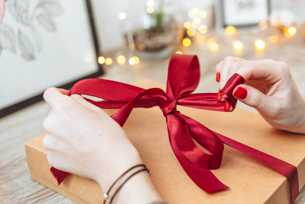Woman wrapping present in paper with red ribbon. - Foto, Imagem