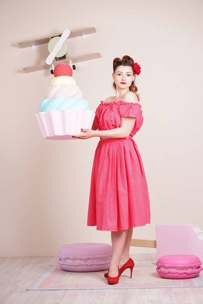 beautiful elegant pin up woman wearing red polka dot dress posing with giant sweets alone - Fotoğraf, Görsel