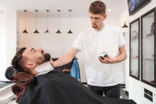 Professional barber working with client in hairdressing salon. Hipster fashion - Фото, изображение