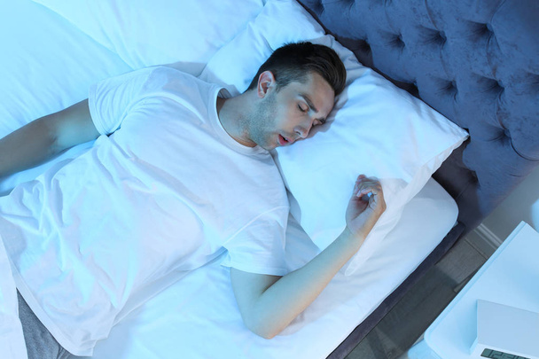 Young man sleeping in bed at night, top view - Fotó, kép