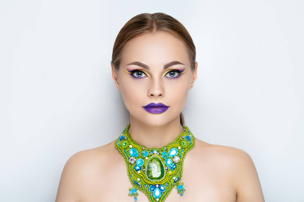New creative make-up, conceptual art idea. eyeshadows, vivid colors graphic shapes lines, cosmetics paints, necklace jewellery. close-up photo. skin painting artistic. perfect straight lines on eyes - Фото, зображення