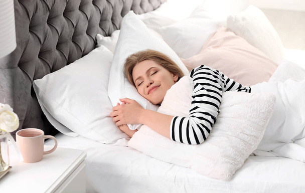 Young woman embracing pillow while sleeping in bed at home - Photo, Image
