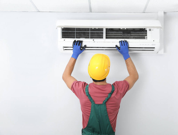 Male technician checking air conditioner indoors - Foto, Imagen