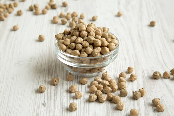 Full bowl of dried chickpeas over white wooden background, side view.  - Fotoğraf, Görsel