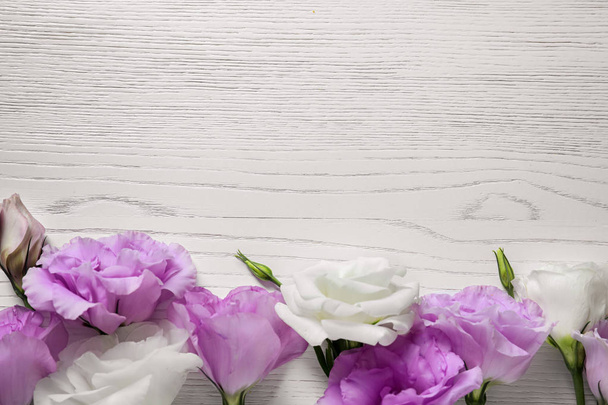 Flat lay composition with beautiful Eustoma flowers on light wooden background - Foto, afbeelding
