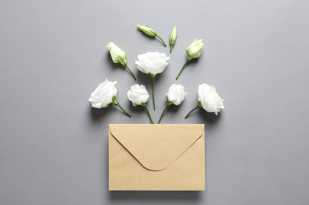 Beautiful Eustoma flowers and envelope on gray background - Фото, зображення