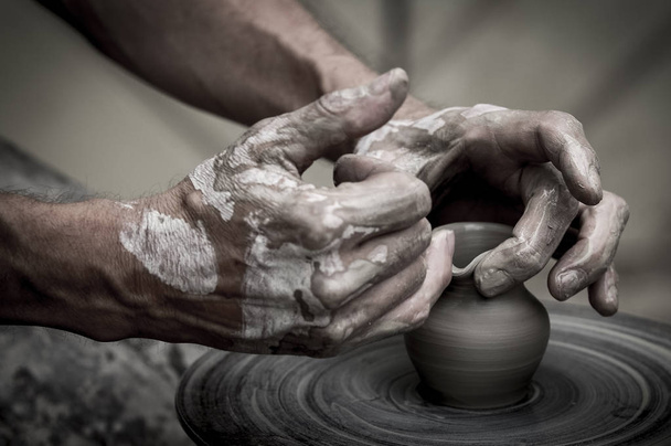 Een ruwe klei pot in de handen van een pottenbakker. Workshop in de pottenbakkerij - Foto, afbeelding
