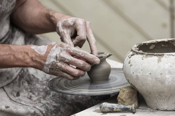 Um pote de barro cru nas mãos de um oleiro. Oficina na oficina de cerâmica
 - Foto, Imagem