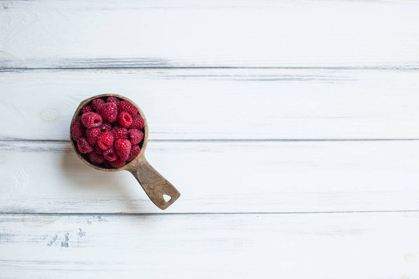 Bowl with summer raspberries on white wooden table. Empty space - Foto, Imagen