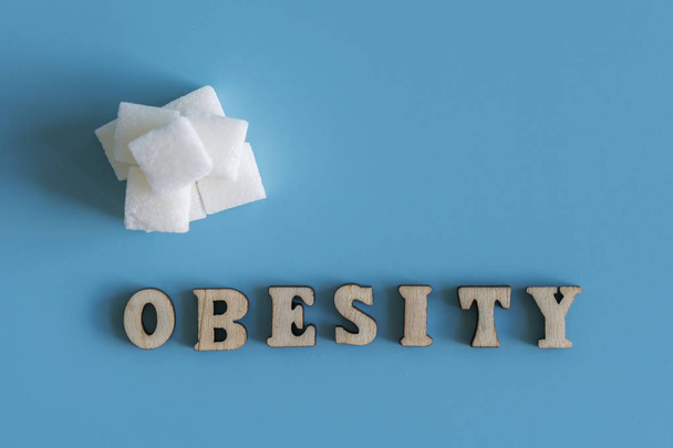 η παχυσαρκία επιγραφή σε μπλε φόντο. Η έννοια της παχυσαρκίας από ζάχαρη. - Φωτογραφία, εικόνα