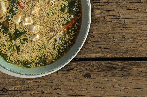 Zupa rybna apetyczny z sezamem w zielony Porcelanowy talerz na szarym tle. Kuchnia Japońska. - Zdjęcie, obraz