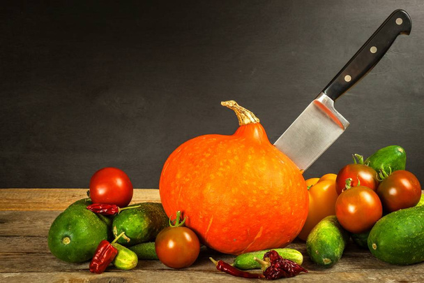 Hokkaido pumpkin on a wooden table with a kitchen knife. Harvesting vegetables on the farm. Slicing the pumpkin. Chef's utensils - Foto, Imagem