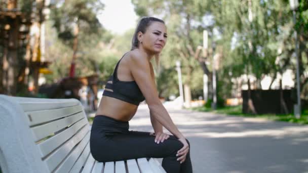 Vrouwelijke atleet runner massage knie pijn, fitness vrouw uitgevoerd in zomer park. - Video