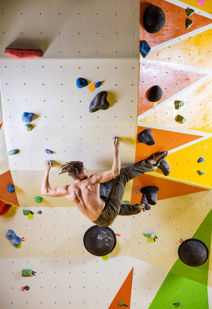 Giovane arrampicata impegnativo percorso di bouldering. In palestra di arrampicata indoor
. - Foto, immagini