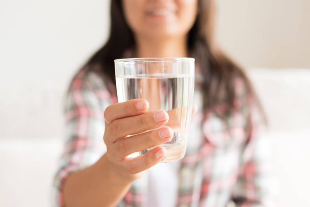 Happy beautiful young woman holding drinking water glass in her hand. Health care concept. - Фото, изображение