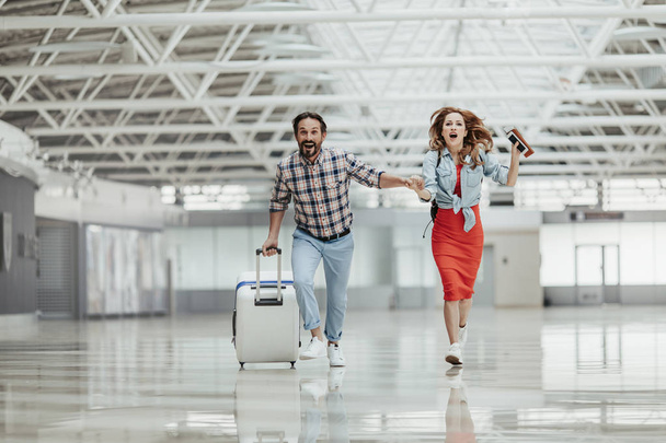 Optimistic male and girl running with baggage - Фото, зображення