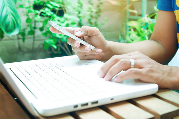 Человек, использующий ноутбук для бизнеса или онлайн-покупок, Селективный фокус на руку с мобильного телефона
 - Фото, изображение