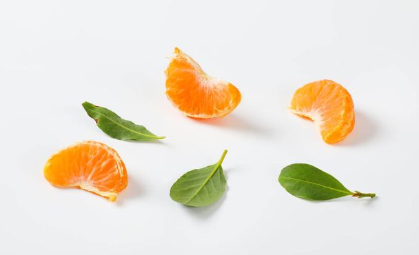Segmente und Blätter der reifen Mandarine auf weißem Hintergrund - Foto, Bild