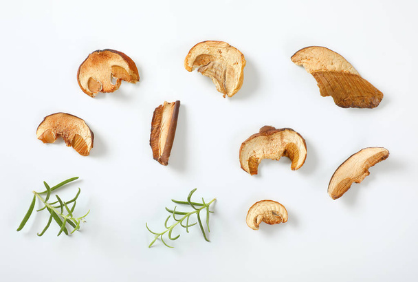 slices of dried mushrooms and rosemary on white background - Foto, Imagem