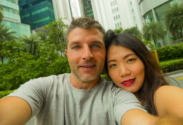 Lifestyle Porträt junger glücklicher und attraktiver gemischter asiatisch-kaukasischer Ethnizität verliebtes Paar beim gemeinsamen Selfie-Foto lächelnd fröhlich Flitterwochen oder Urlaubsreisen genießend  - Foto, Bild