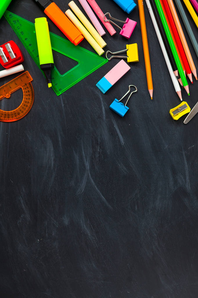 Concept de retour à l'école. Fournitures scolaires sur fond de tableau noir, accessoires pour la salle d'école - crayons, ciseaux, craie, marqueurs. Copier l'espace vue supérieure
 - Photo, image