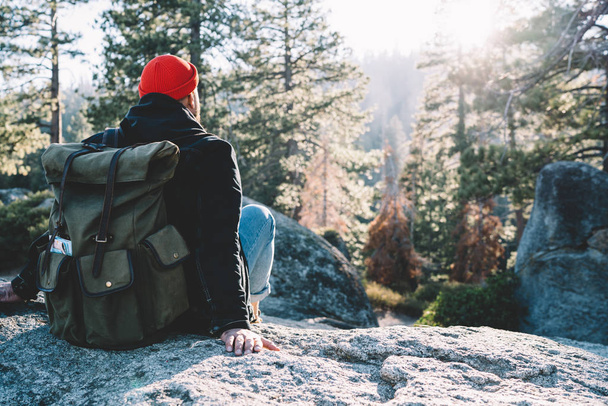 Male hiker with rucksack resting during trekking tour in mountains wanderlust on weekend journey,back view of hipster guy looking at scenery of wild forests in Yosemite national park exploring natur - Фото, изображение