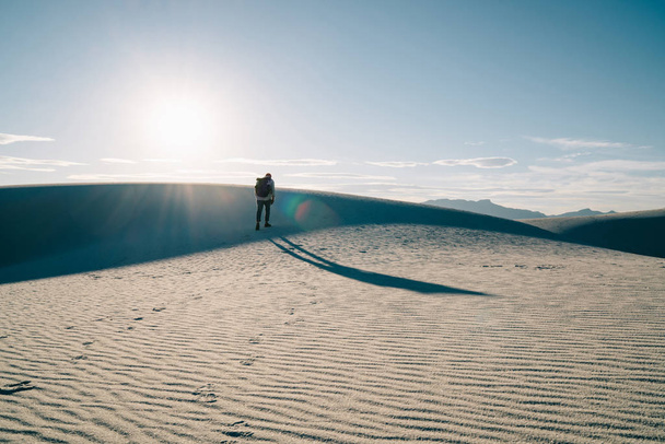 Male person silhouette walking in wild desert lands exploring arid nature landscape with dunes,man traveling in White sands national park getting to destination with rucksack on weekend journe - Фото, зображення