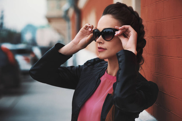 beautiful woman wearing sunglasses and black leather jacket looking aside - Zdjęcie, obraz