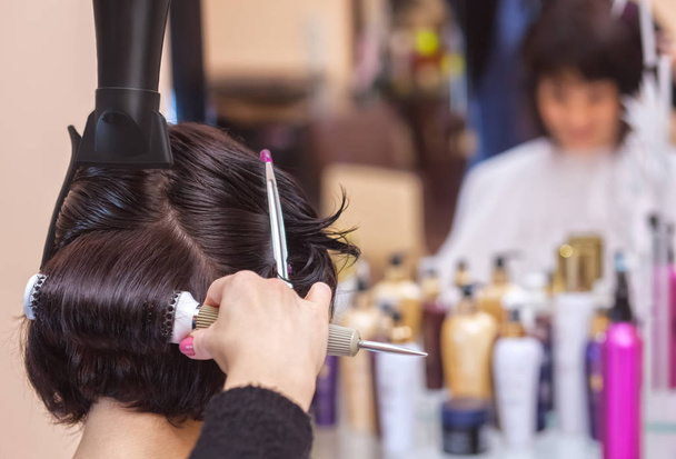 Le coiffeur sèche ses cheveux une fille brune dans un salon de beauté
. - Photo, image