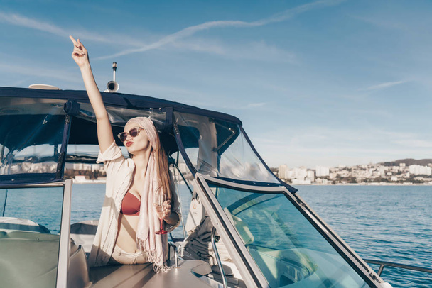 a gorgeous cheerful girl in sunglasses enjoys relaxing on a yacht, sails on the Caribbean sea - Фото, зображення