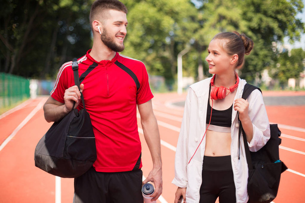 Молодий спортивний чоловік і дівчина з навушниками щасливо проводять час разом на біговій доріжці стадіону
 - Фото, зображення