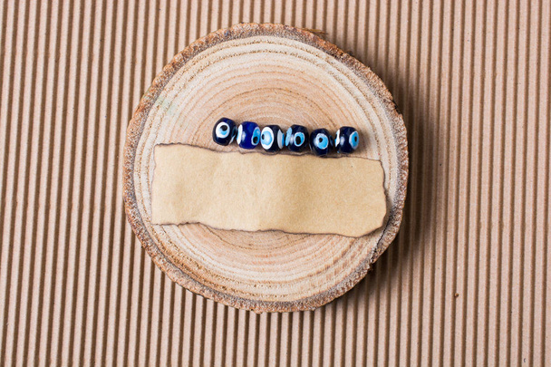 Boze oog kralen en stuk van verbrand papier op hout log - Foto, afbeelding