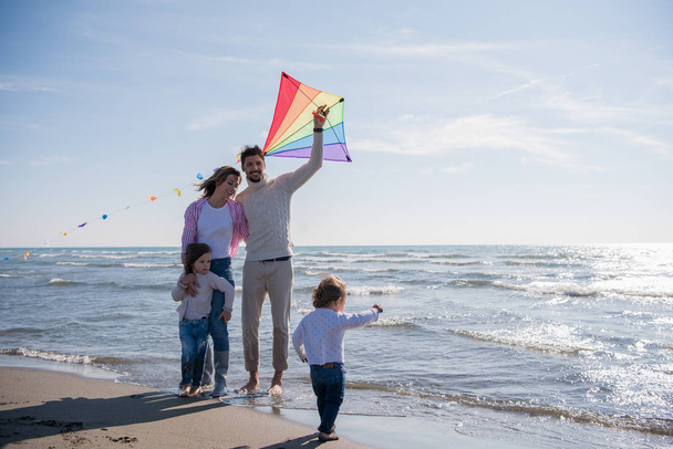young family with kids resting and having fun with a kite at beach during autumn day - Foto, Bild