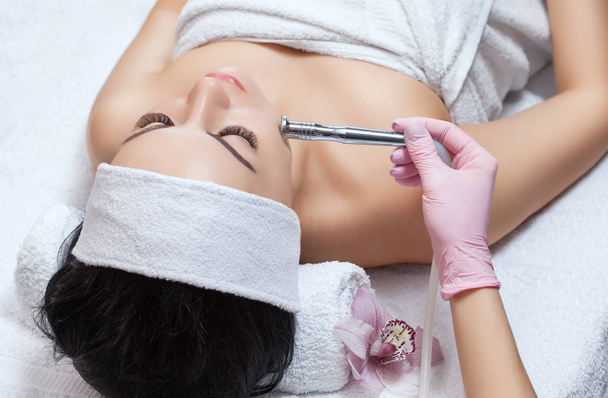 Le cosmétologue effectue la procédure Microdermabrasion de la peau faciale d'une belle jeune femme dans un salon de beauté.. - Photo, image