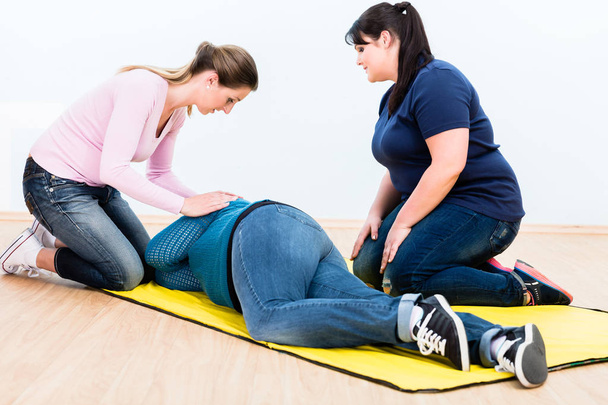 Mujeres en entrenamiento de primeros auxilios para posicionar a una persona lesionada
 - Foto, Imagen