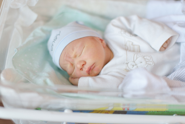 новонароджена дитина лежить у дитячому ліжечку в пренатальній лікарні
 - Фото, зображення