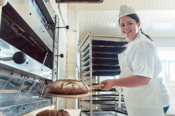 Пекарь получает свежий хлеб с лопатой из духовки
 - Фото, изображение