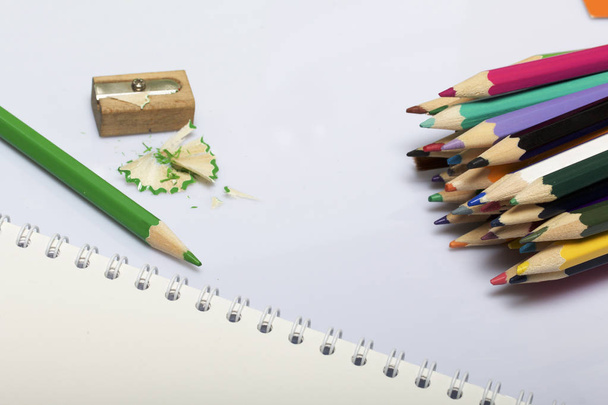 Stationery for school and teaching. Notepad and colored pencils for writing and drawing. Pencil sharpener with pencil shaving. - Foto, imagen