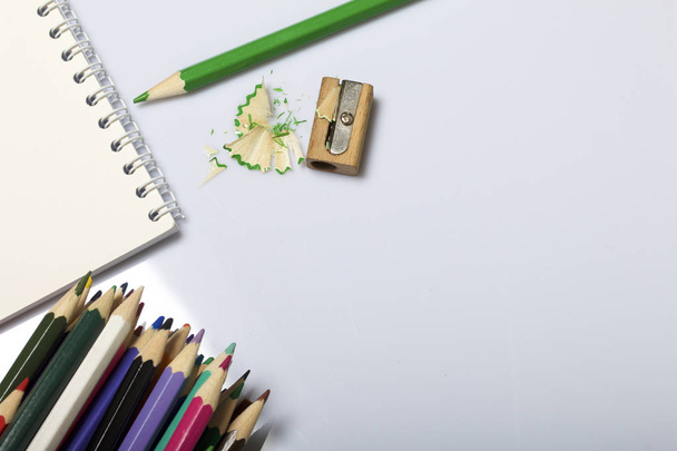 Stationery for school and teaching. Notepad and colored pencils for writing and drawing. Pencil sharpener with pencil shaving. - Fotoğraf, Görsel