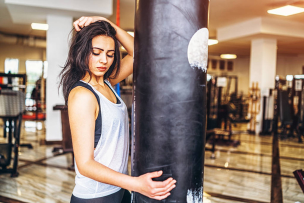 attractive sporty woman touching leather punching bag in gym - Foto, Imagen