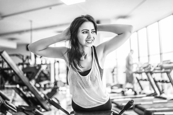 Pretty sporty woman doing abdominal exercises on bench in gym  - Φωτογραφία, εικόνα