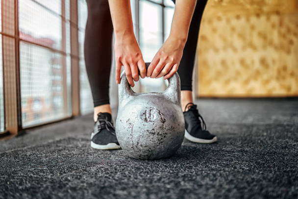 Sporty woman lifting kettlebell from floor in gym - Foto, Imagem