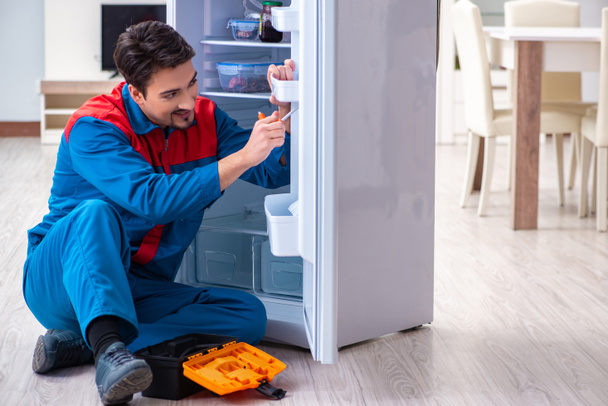 Profesyonel müteahhit bozuk buzdolabını tamir ediyor. - Fotoğraf, Görsel