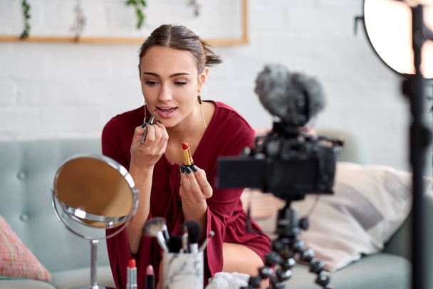 Pretty woman recording video blog vlog and doing make up and applying lipstick - Foto, Imagem